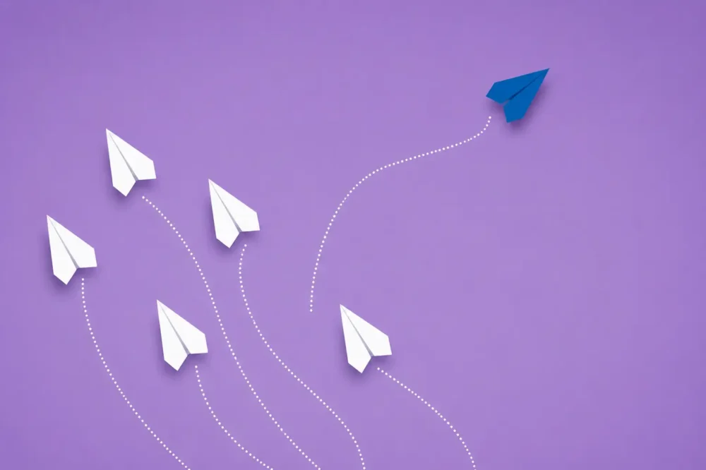 Avions en papier alignés à l'exception d'un bleu qui marque sa différence à l'image de l'année 2026 en paie.