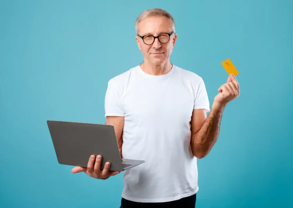 Homme tenant un ordinateur portable et une carte de crédit, représentant la gestion de la TVA pour les auto-entrepreneurs.