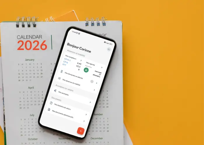 Smartphone affichant une interface RH posé sur un calendrier 2026, illustrant la digitalisation et la planification des temps de travail.